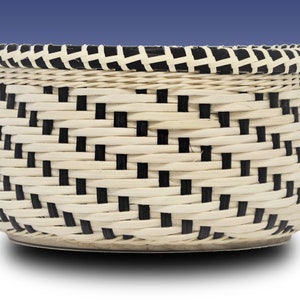 May include: A woven basket with a black and white checkered pattern. The basket is made of natural materials and has a round shape.