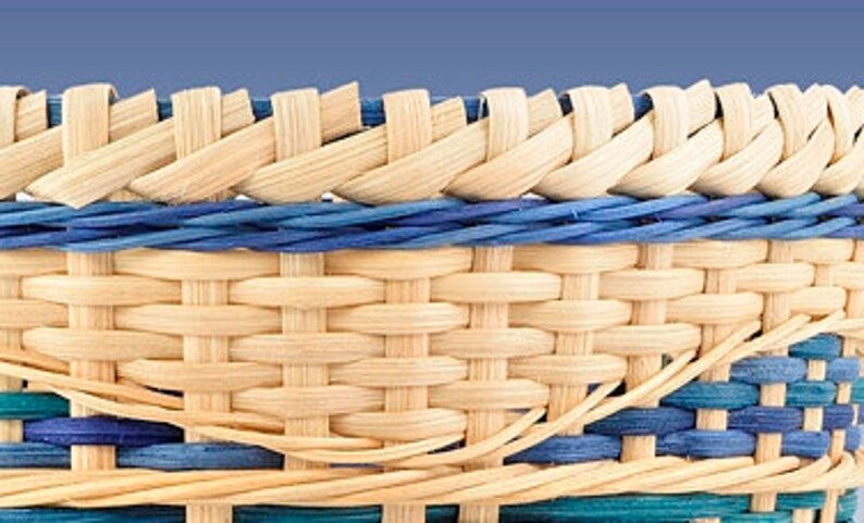 May include: Close-up of a woven basket with a natural brown color and blue and teal accents. The basket is made with a tight weave and has a smooth, polished finish.