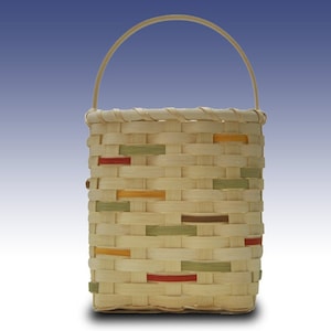 May include: A small, woven basket with a natural wood handle. The basket is made of light brown wicker with colourful accents of red, orange, and green.