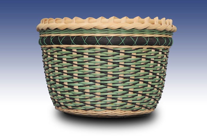 May include: A woven basket with a green and black pattern. The basket is made of natural materials and has a rounded shape.