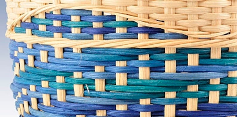 May include: Close-up of a woven basket with a pattern of blue and teal stripes. The basket is made of natural materials and has a light brown color.