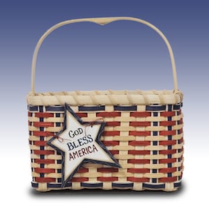 May include: A woven basket with a red, white, and blue American flag design. The basket has a wooden handle and a star-shaped tag that says "God Bless America".