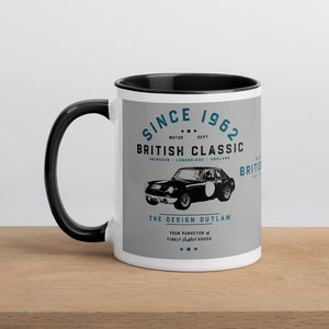 May include: White ceramic mug with a black rim and handle. The mug features a vintage-style graphic of a classic British car with the text "Since 1962 British Classic The Design Outlaw".