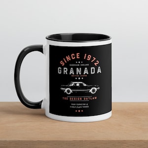Może przedstawiać: Biały kubek ceramiczny z czarnym rantem i uchwytem. Kubek ma czarny wzór z tekstem "Since 1972 Dagenham England Granada British Legend The Design Outlaw Your purveyor of finely crafted goods" i sylwetkę samochodu.