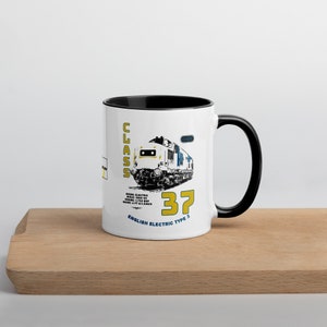 May include: White ceramic mug with a black rim and handle. The mug features a black and white illustration of a train with the text "CLASS 37 ENGLISH ELECTRIC TYPE 3" in yellow and blue.