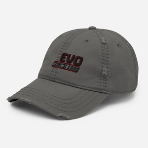Op de afbeelding: Een grijze, verweerde baseballpet met zwarte en rode geborduurde tekst die "EVO SINCE 1992" luidt.