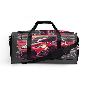 May include: A black and gray duffel bag with a red and white graphic of a sports car. The bag has a black zipper and a black handle.