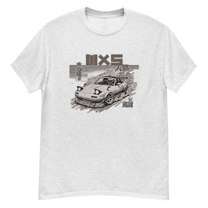 Könnte beinhalten: Ein graues T-Shirt mit einer weißen und grauen Illustration eines Autos mit dem Text "MX5" auf der Vorderseite.