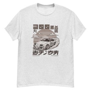 May include: A gray t-shirt with a graphic of a white Nissan 280ZX with the text "HACHIROKU  DRIFTED" on the side of the car. The text "300ZX", "六", "drift", and "西テクノサファ" are also on the shirt.