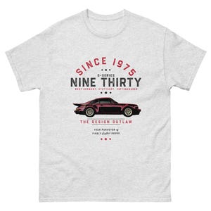 May include: A grey t-shirt with a red and white graphic design featuring a vintage car and the text "Since 1975 G-Series Nine Thirty West Germany: Stuttgart, Zuffenhausen... The Design Outlaw Your Purveyor of Finely Crafted Goods..."
