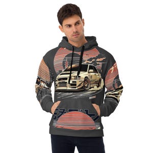 Puede incluir: Sudadera con capucha gris oscuro con un diseño de coche deportivo blanco y gráficos de inspiración japonesa. El diseño incluye un sol naciente, nubes y texto japonés. La sudadera tiene un bolsillo delantero y una capucha con cordón.