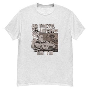 May include: Light grey t-shirt with a graphic of a car, the text "TOKYO, JAPAN", Japanese characters, a wave, and the year "1978". The shirt is made of a soft, comfortable material.