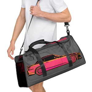 May include: Gray travel duffel bag with a black shoulder strap and a pink and orange car graphic on the front. The car graphic has the text "LEGEND" on the side.