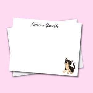 Puede incluir: Una tarjeta de papelería rectangular blanca con el texto negro Emma Smith centrado en la parte superior y una pequeña ilustración de un gatito blanco y negro en la esquina inferior derecha. La tarjeta está sobre un sobre a juego.