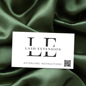 Puede incluir: Una tarjeta de visita blanca con texto negro que dice "LE Lash Extension" e "Instrucciones de cuidado posterior". Un c&oacute;digo QR en blanco y negro se encuentra en la esquina inferior derecha.