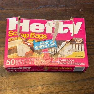 Puede incluir: Una caja rosa y blanca de Hefty Scrap Bags. La caja dice "NEW! WHITE BAG" y "50 BOLSAS CON ATADURAS DESPRENDIBLES 16,5 cm x 14 cm x 0,28 mm". La caja también dice "LEAKPROOF" y "NURSERY".