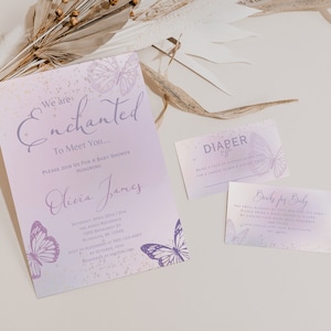 Op de afbeelding: Paarse en gouden babyborrel uitnodiging met een vlinderontwerp. De uitnodiging luidt "We are Enchanted to Meet You..." en bevat de tekst "Please join us for a baby shower honoring Olivia James".