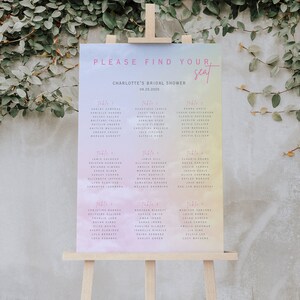 Puede incluir: Un fondo de acuarela en tonos pastel rosa, amarillo y azul con un marco blanco y texto negro. El texto dice "Por favor, encuentra tu asiento" y "Charlotte's Bridal Shower 08.25.2025". El texto está dividido en seis mesas con los nombres de los invitados listados debajo de cada número de mesa.