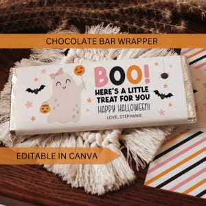May include: A rectangular chocolate bar wrapper featuring a white background with a cartoon ghost wearing a pink bow, holding a pumpkin lollipop and a trick-or-treat bucket. The text reads BOO! HERE'S A LITTLE TREAT FOR YOU HAPPY HALLOWEEN! LOVE, STEPHANIE.