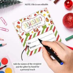 May include: A red and green striped gift tag with a Christmas theme. The tag has a white oval with the word "Christmas" in yellow letters. The tag has spaces to write "To:" and "From:".