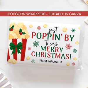 Puede incluir: Envoltorio de palomitas con un diseño navideño. El envoltorio presenta un cubo de palomitas con un lazo verde, palomitas de maíz y el texto "just POPPIN' BY to say MERRY CHRISTMAS!" en rojo y verde. También se incluye el texto "FROM SAMANTHA".