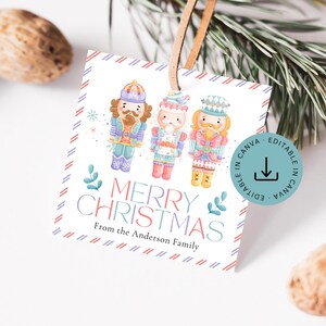 Könnte beinhalten: Ein quadratisches Weihnachtsgeschenkanhänger mit einem braunen Lederband. Das Etikett zeigt drei farbenfrohe Nussknacker-Illustrationen und den Text "MERRY CHRISTMAS" in einer Regenbogen-Schriftart. Das Etikett enthält auch den Text "From the Anderson Family".