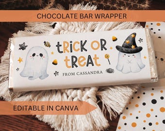 May include: A rectangular chocolate bar wrapper featuring a white background with two cartoon ghosts, one wearing a black witch hat. The text reads TRICK OR TREAT and FROM CASSANDRA in black and orange, surrounded by small stars, candy, and a spider.