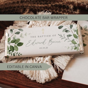 Op de afbeelding: Een witte chocoladereepverpakking met groene bladeren en de tekst "The Baptism of Edward Brian 05.10.26". De verpakking heeft een gouden kruis en is gelabeld met "Chocolate Bar Wrapper" en "Editable in Canva".