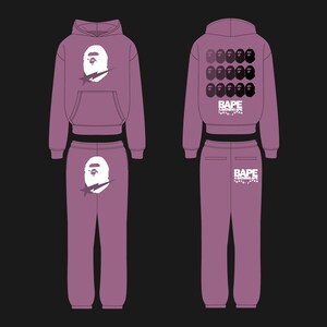 May include: A mauve hoodie and sweatpants set. The hoodie features a white graphic of a cartoon ape head with a star. The sweatpants have the same graphic on the front and the brand name on the back. The set is displayed on a black background.
