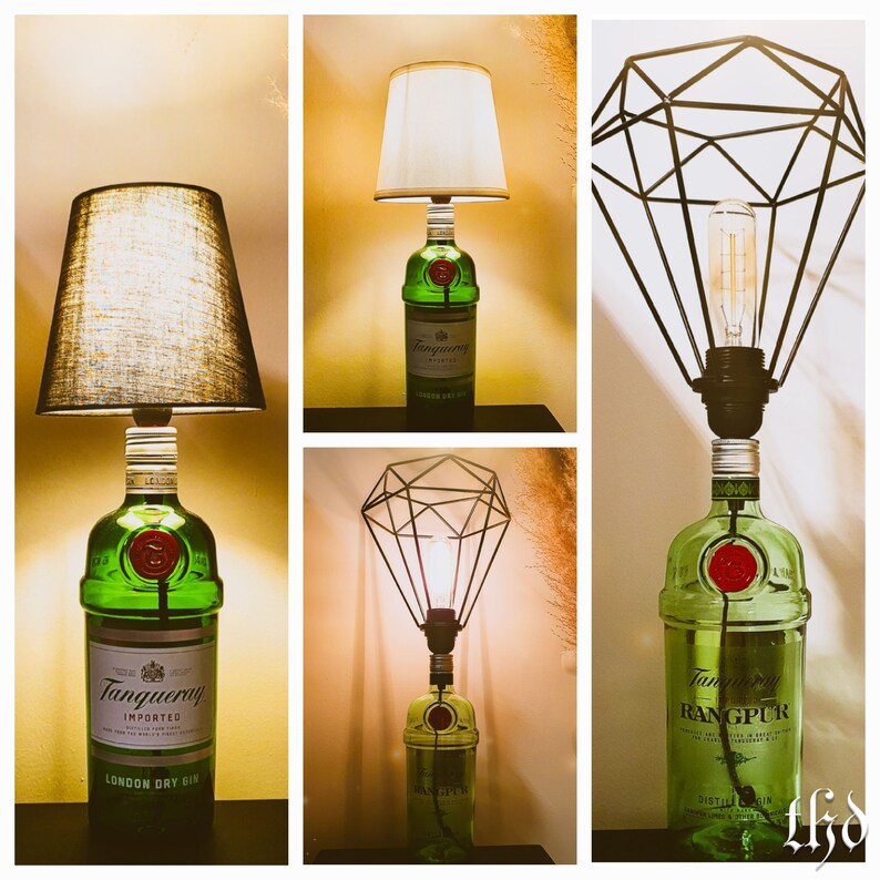 May include: Three different lamps made from repurposed liquor bottles. The lamps are all green glass and have a black metal shade. The first lamp has a white fabric shade, the second lamp has a black metal diamond-shaped shade, and the third lamp has a black metal cage shade. The bottles all have labels that say "Tanqueray" and "Rangpur".