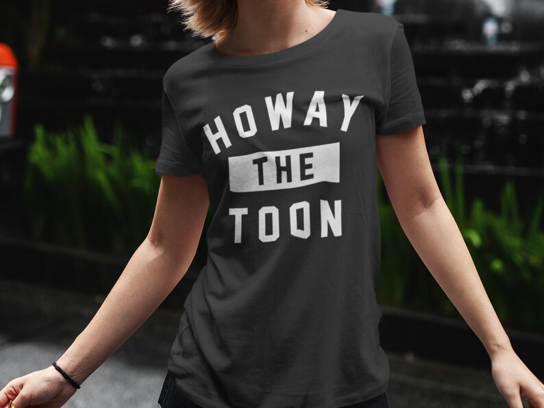 Op de afbeelding: Zwart T-shirt met witte tekst die "Howay the Toon" zegt.