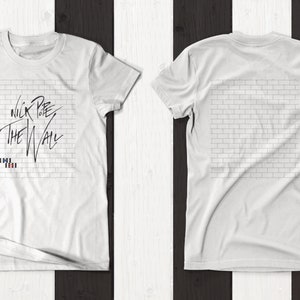 Pode incluir: Camiseta branca com uma imagem em preto e branco de uma parede de tijolos e o texto "Nick Lowe The Wall" na frente. A parte de tr&aacute;s da camiseta apresenta um design de parede de tijolos.