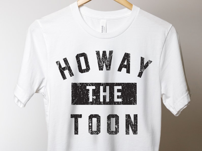 May include: White t-shirt with black text that reads "HOWAY THE TOON".