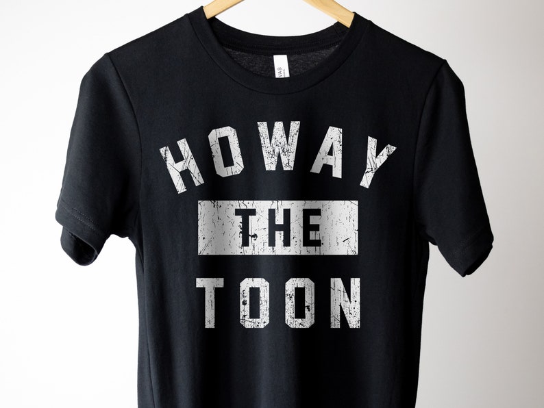 May include: Black t-shirt with white text that reads "Howay the Toon" in a distressed font.