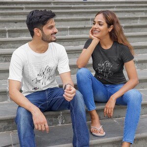 Pode incluir: Duas pessoas vestindo camisetas com um gr&aacute;fico de uma parede de tijolos e o texto "Nick Cave The Wall" nela. As pessoas est&atilde;o sentadas em um conjunto de escadas de concreto.