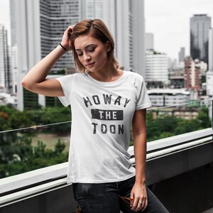 May include: A white t-shirt with a black graphic that says "Howay the Toon".