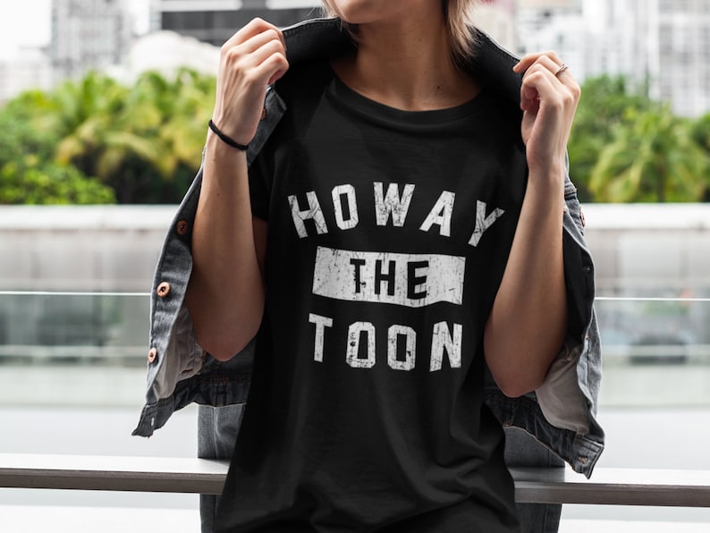May include: Black t-shirt with white text that reads "Howay the Toon" in a distressed font.