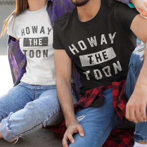 May include: A couple wearing matching t-shirts with the text "Howay the Toon" in a distressed white font on a black and white background.