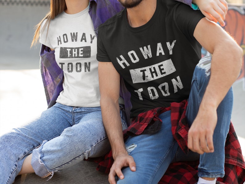 May include: A couple wearing matching t-shirts with the text "Howay the Toon" in a distressed white font on a black and white background.
