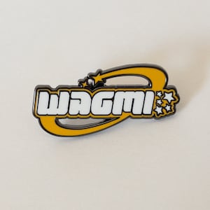 May include: A rectangular pin with the word "WAGMI" in white block letters, outlined in black, and set against a yellow background. The pin features a shooting star and star accents, all with a black border.