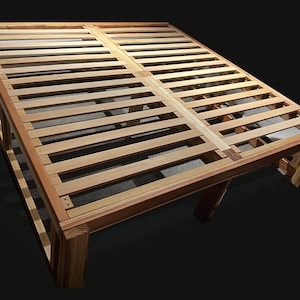 May include: A wooden bed frame with a slatted base. The frame is made of natural wood with a light brown finish. The slats are evenly spaced and provide support for a mattress.