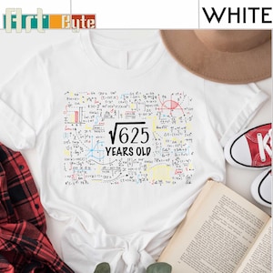 May include: White t-shirt with a graphic of mathematical equations and the text "√625 YEARS OLD". The shirt has a crew neck and short sleeves. A red and white shoe is visible in the background.