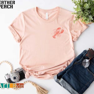a pink t - shirt with a lobster on it