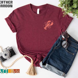 a t - shirt with a crab on it next to a pair of jeans and