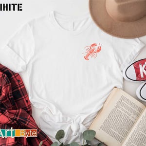 a white shirt with a red crab on it