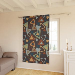 May include: A single curtain panel hanging on a metal rod, featuring a dark brown background with a repeating pattern of overlapping triangles in shades of light blue, sage green, mustard yellow, and burnt orange throughout the fabric.