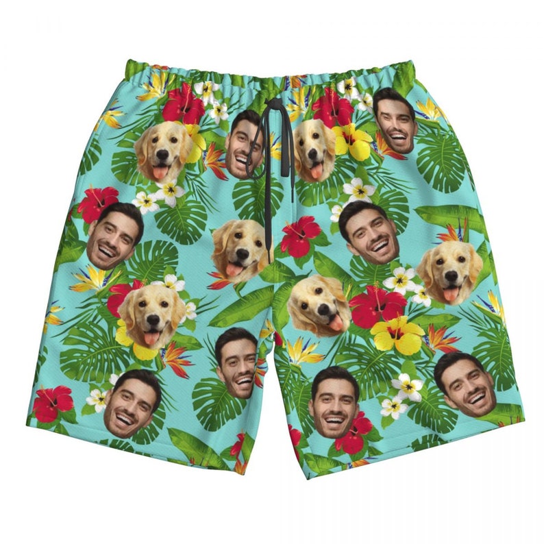 Puede incluir: Ba&ntilde;ador azul con estampado tropical que incluye caras de personas y perros. El estampado incluye hojas verdes, flores rojas y amarillas, y una variedad de otras plantas tropicales.
