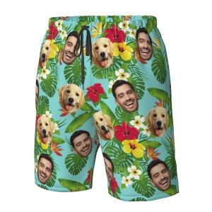 Puede incluir: Un par de pantalones de ba&ntilde;o azules con un estampado tropical que presenta un patr&oacute;n repetitivo de flores, hojas y caras de un hombre y un perro.