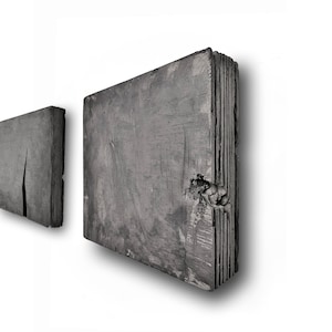 May include: Two gray, rectangular, stacked concrete wall sculptures with rough, textured surfaces.