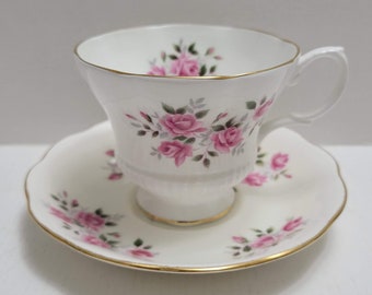 May include: A white teacup and saucer set with a pink rose floral pattern and gold trim.